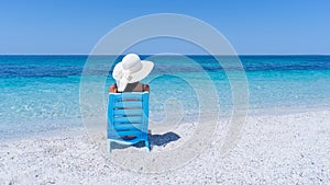 girl with white straw hat relaxes in front of the sea photo